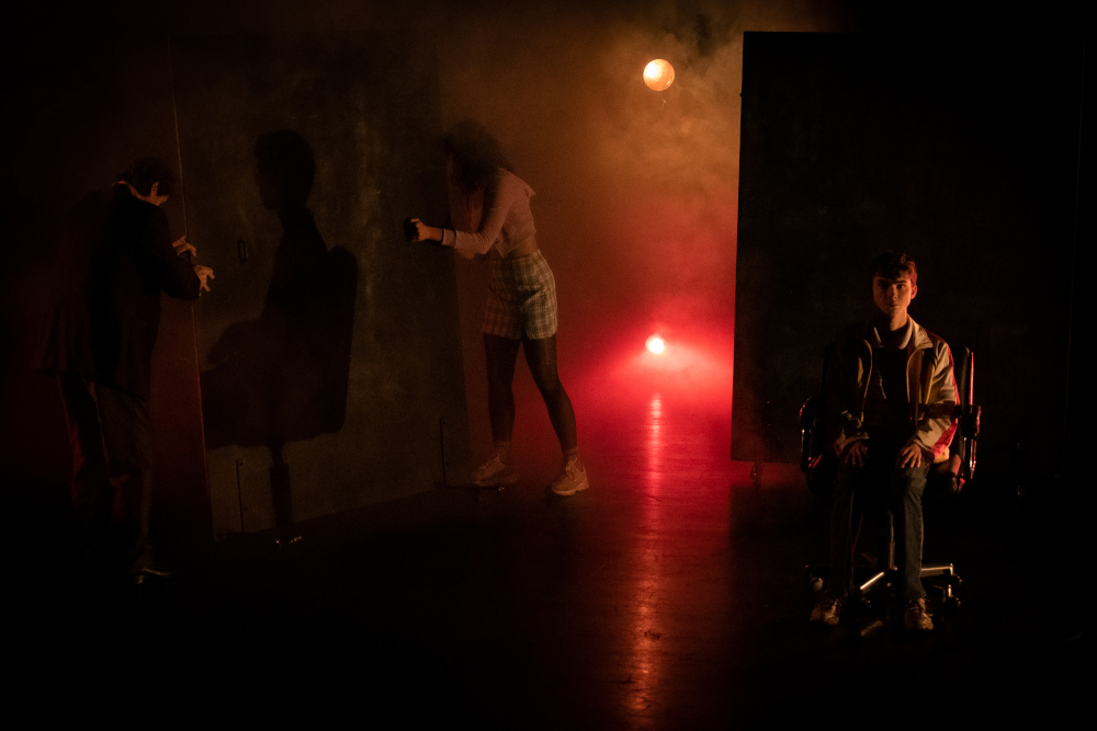 Un comédien est assis dans une lumière rouge et orange avec de la fumée, création lumière de Jérôme Baudouin, créateur lumière en danse, théâtre et spectacle vivant